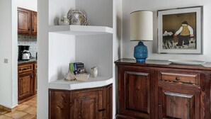 A kitchen with wooden cabinets, a white countertop, a blue vase, and a framed painting on the wall. - Villa Romana – Beach House with Fenced Garden at Costa Rei (Costa Rei)