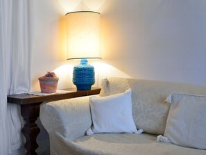A cozy room with a sofa, a lamp, and a small table with a vase.