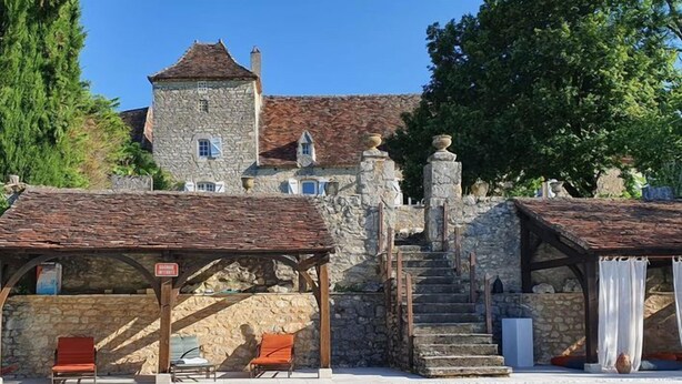 Un edificio de piedra con piscina, mobiliario exterior y una escalera que lleva a una torre.