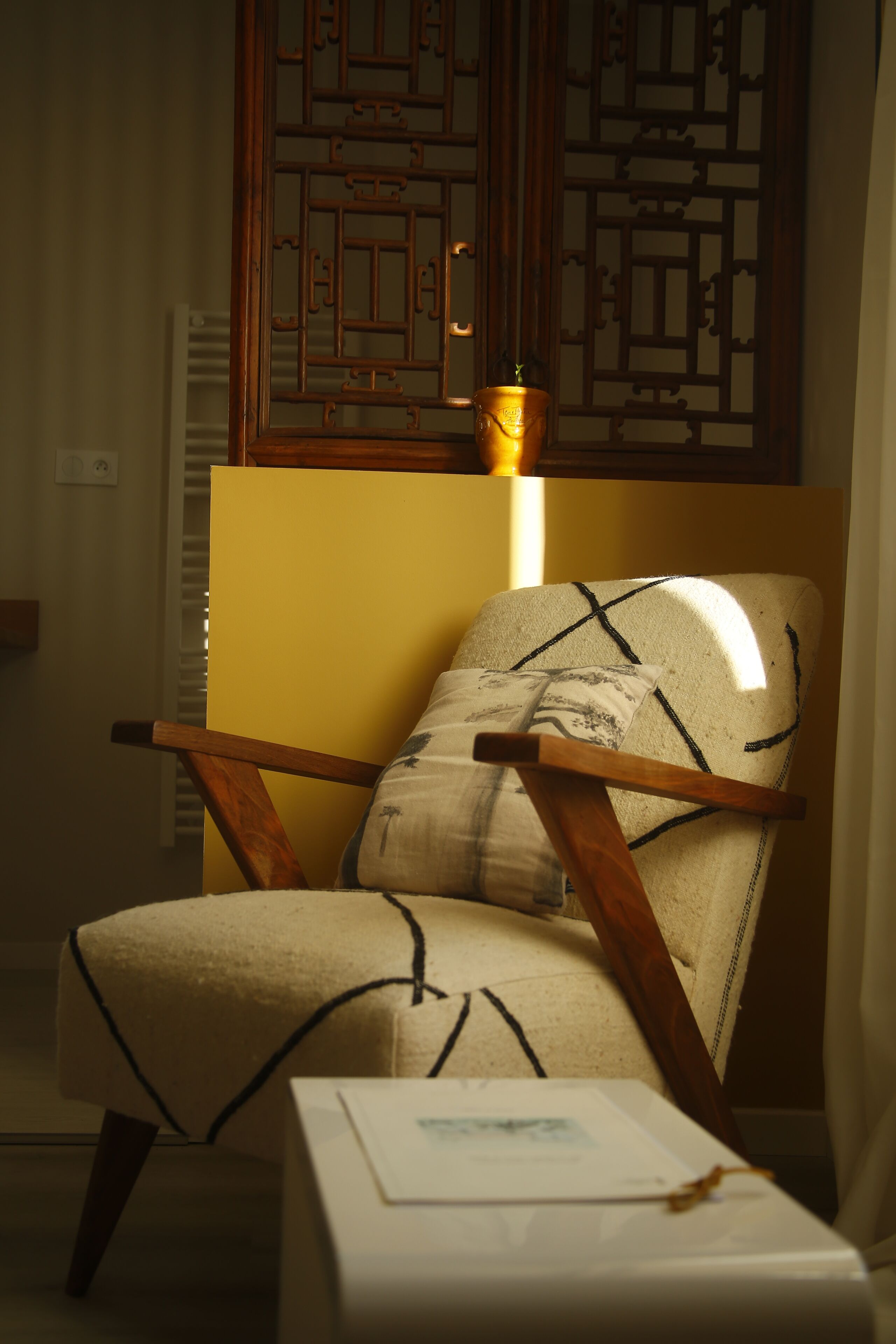 A chair with a cushion and a small table with a document.