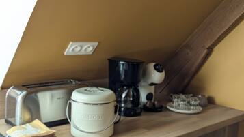 A kitchen counter with a toaster, a coffee maker, a compost bin, and a kettle.
