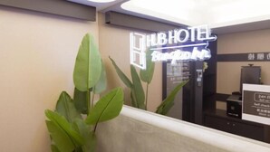 A hotel reception area with a neon sign for 'HUBHOTEL Bangkok' and a self-checkout machine.