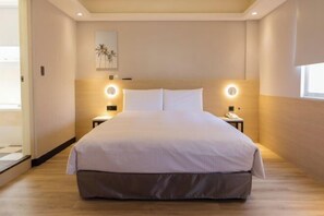 A modern hotel room with a large bed, bedside tables, and a ceiling light fixture. - Hub Hotel Banqiao Inn (New Taipei City)