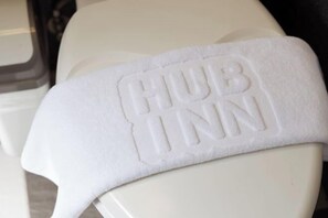 A white towel with "HUB INN" embossed on it, draped over a white chair. - Hub Hotel Banqiao Inn (New Taipei City)