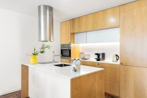 A modern kitchen with wooden cabinets, a stainless steel range hood, a built-in microwave, and a white countertop. - An Urban Retreat with a Balcony | Bright & Central in Porto (Porto)