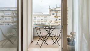 A balcony with a table and chairs, a potted plant, and a view of buildings. - Urban Retreat w/ Balcony | Bright & Central Porto (Porto)