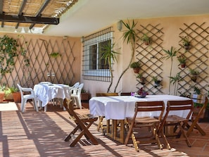 An outdoor patio with tables and chairs, potted plants, and a lattice wall. - Villa Mimosa: Private Villa with Panoramic Terrace near Pula (Pula)