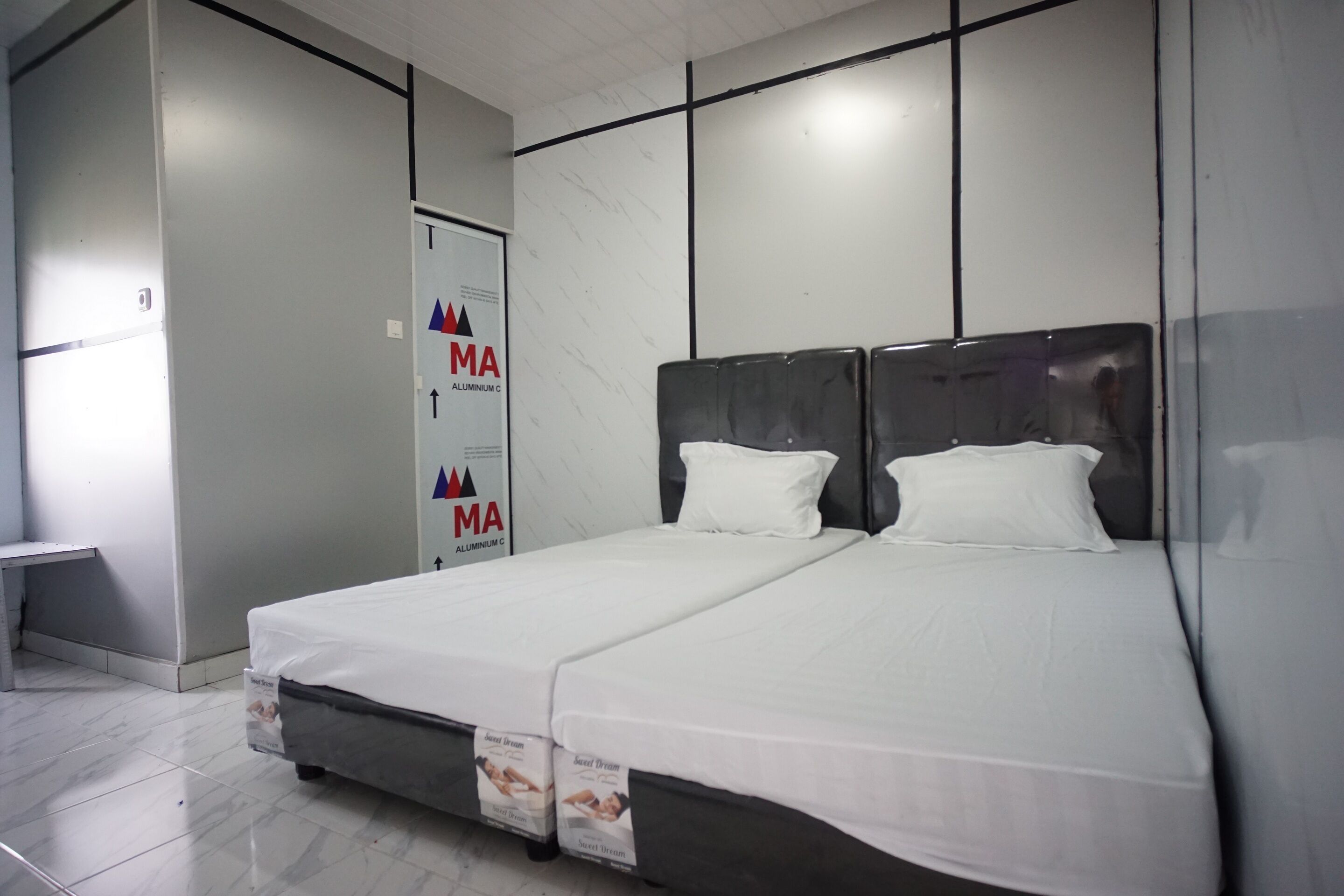 A hotel room with a large bed, a desk, and a wardrobe.