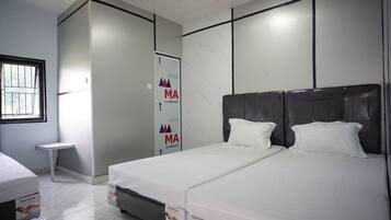 Habitación de hotel con dos camas, una mesita y un armario.
