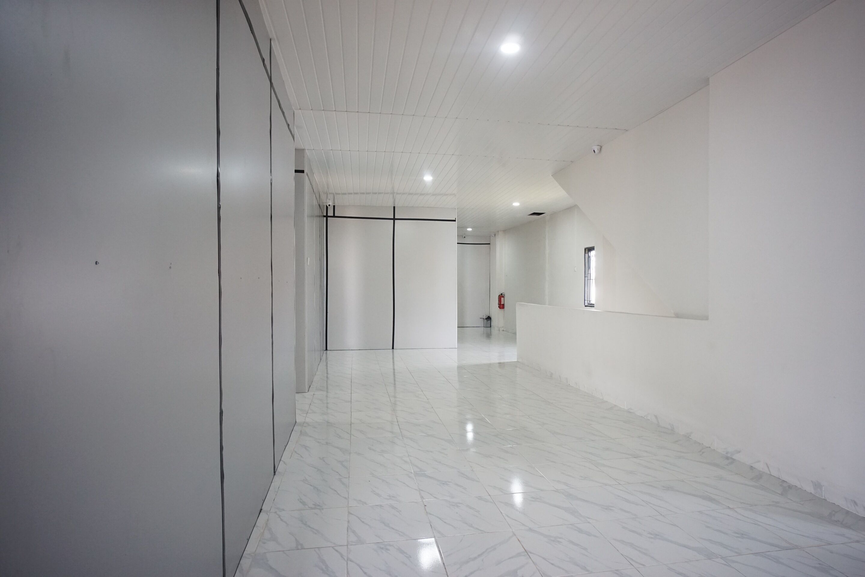 A spacious, modern interior with a polished marble floor, white walls, and recessed ceiling lighting.