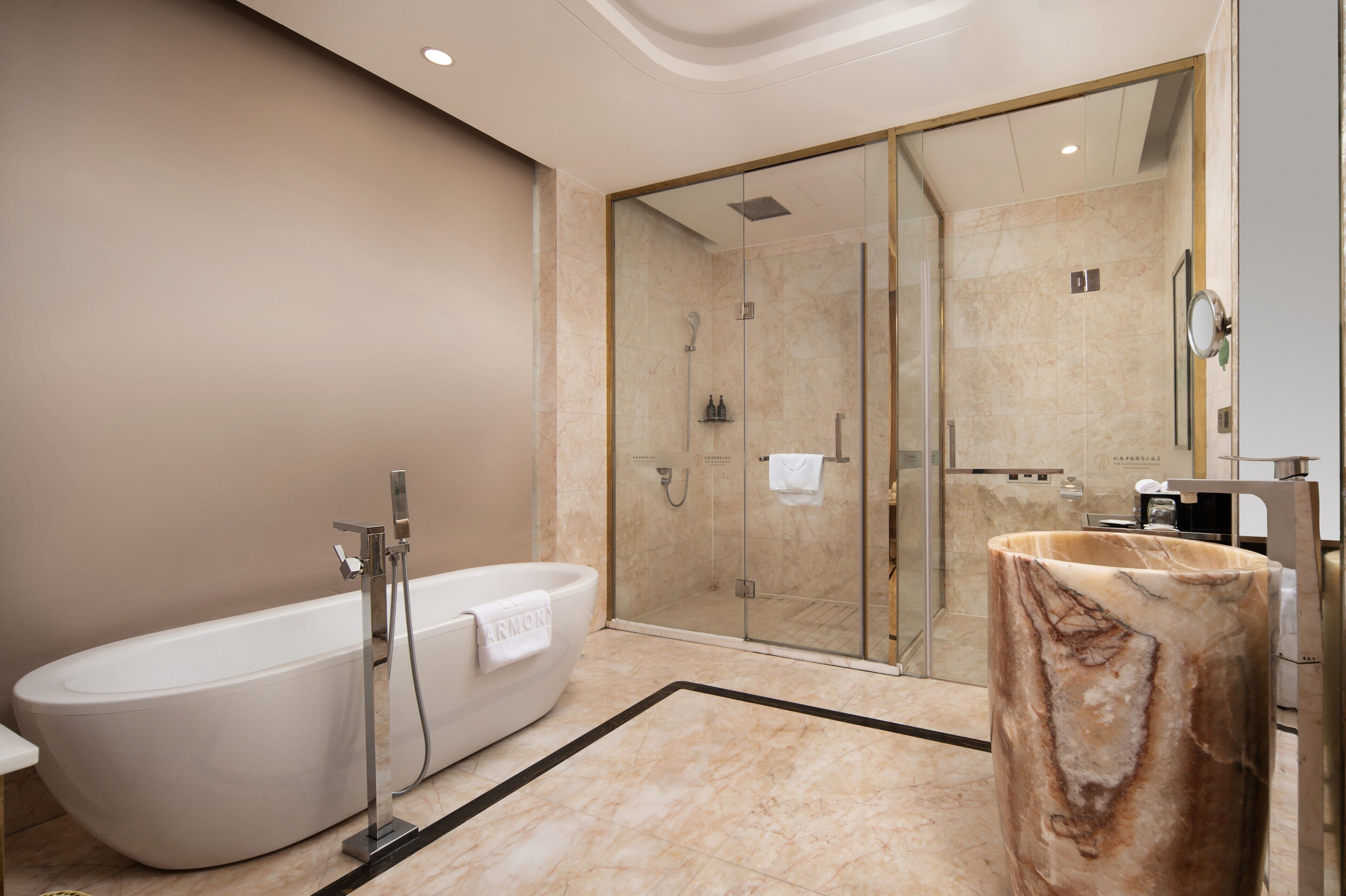 Ein modernes Badezimmer mit freistehender Badewanne, einer in Glas eingefassten Dusche und einem Marmorwaschbecken.