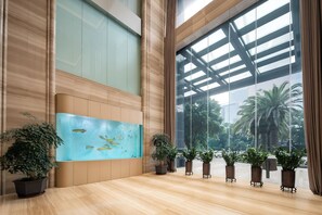 Un hall d’entrée spacieux, agrémenté d’un grand aquarium, de plantes en pot et offrant une vue sur les palmiers à travers de grandes fenêtres.