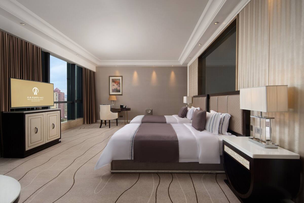 Una habitación de hotel con una cama grande, un escritorio, un televisor y vistas a la ciudad.