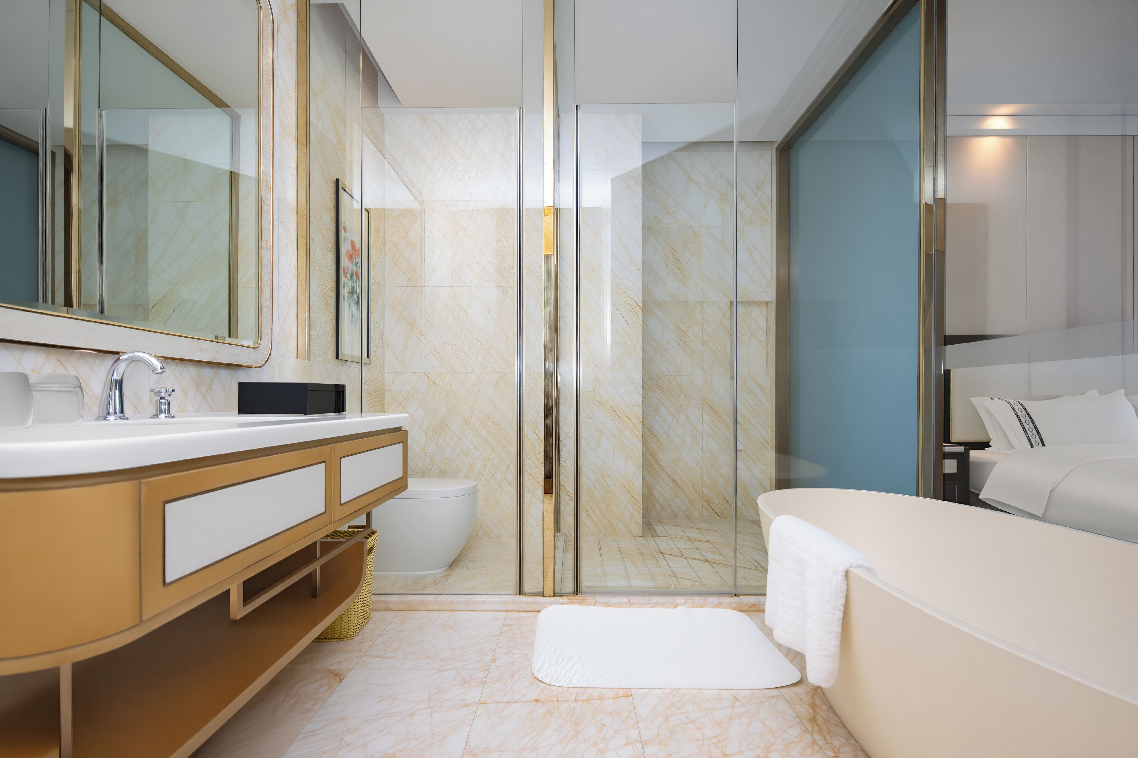 Casa de banho moderna com cabine de duche em vidro, lavatório branco com toucador dourado e um espelho grande.