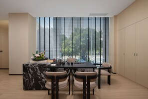 Une cuisine moderne dotée d’un îlot en marbre, de quatre chaises et offrant une vue dégagée grâce à de grandes fenêtres.