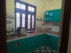 Una cocina con gabinetes color turquesa, piso a cuadros y una ventana con persianas.