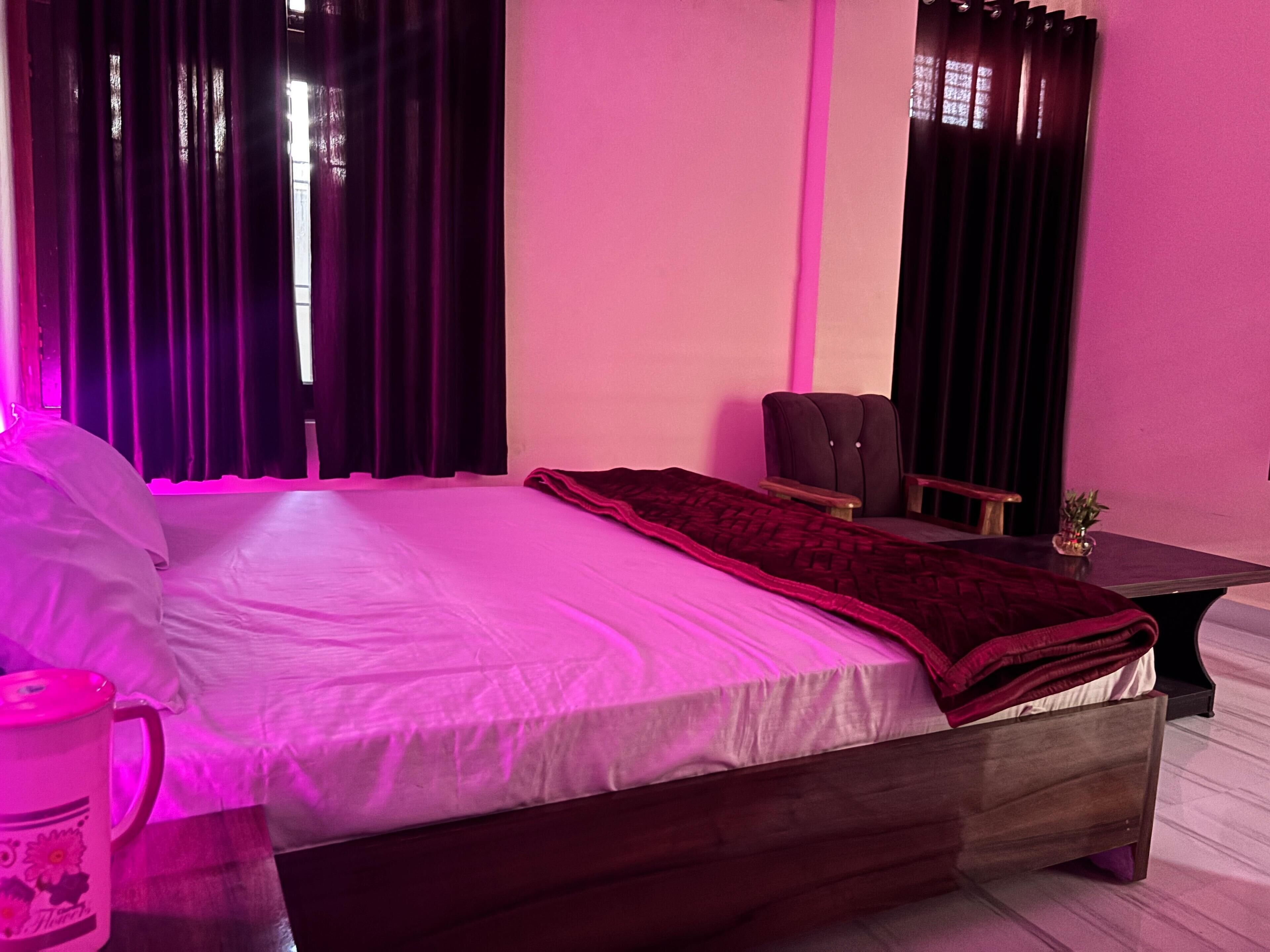 Une chambre à coucher avec un lit, une chaise, une table de chevet et une fenêtre avec des rideaux.