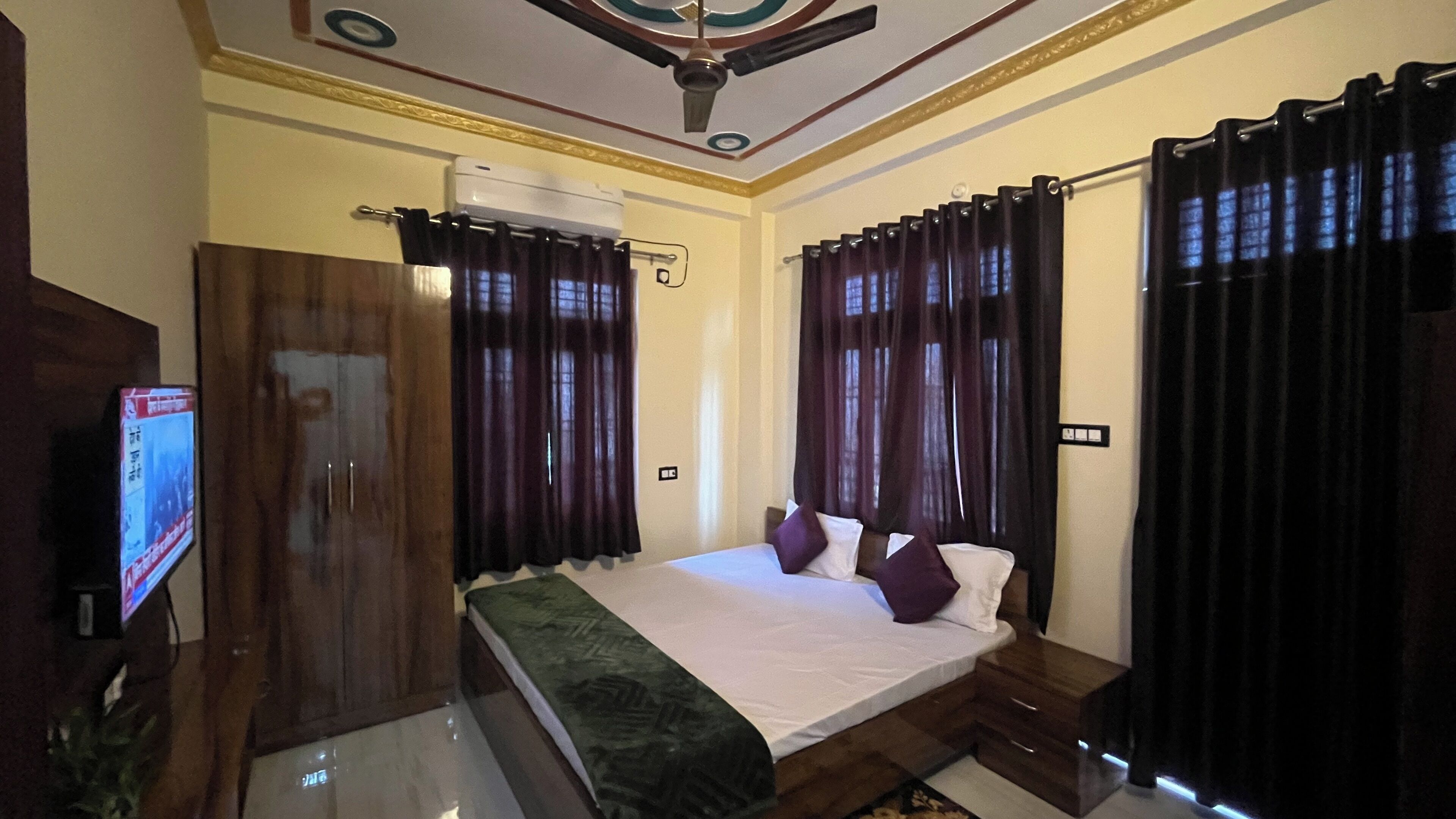 A hotel room with a bed, a TV, a wardrobe, and curtains.