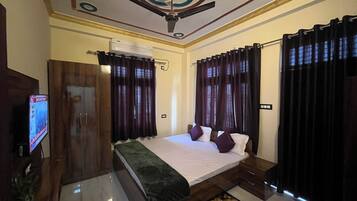 A hotel room with a bed, a TV, a wardrobe, and curtains.