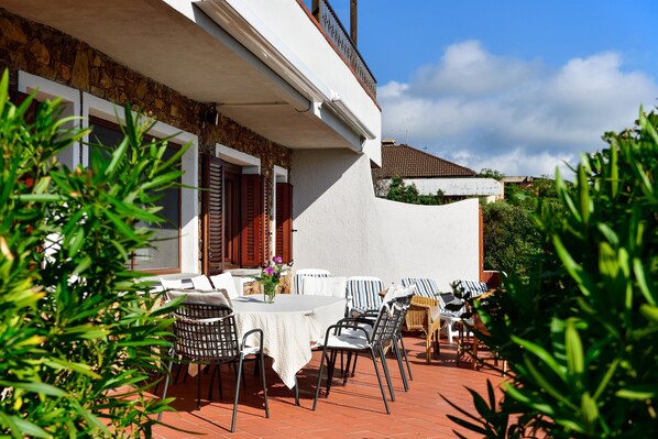 Un patio con mobiliario exterior, una mesa con un florero y una pared de piedra.