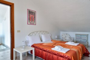 Un dormitorio con cama, mesitas de noche, lámpara, silla y cómoda.