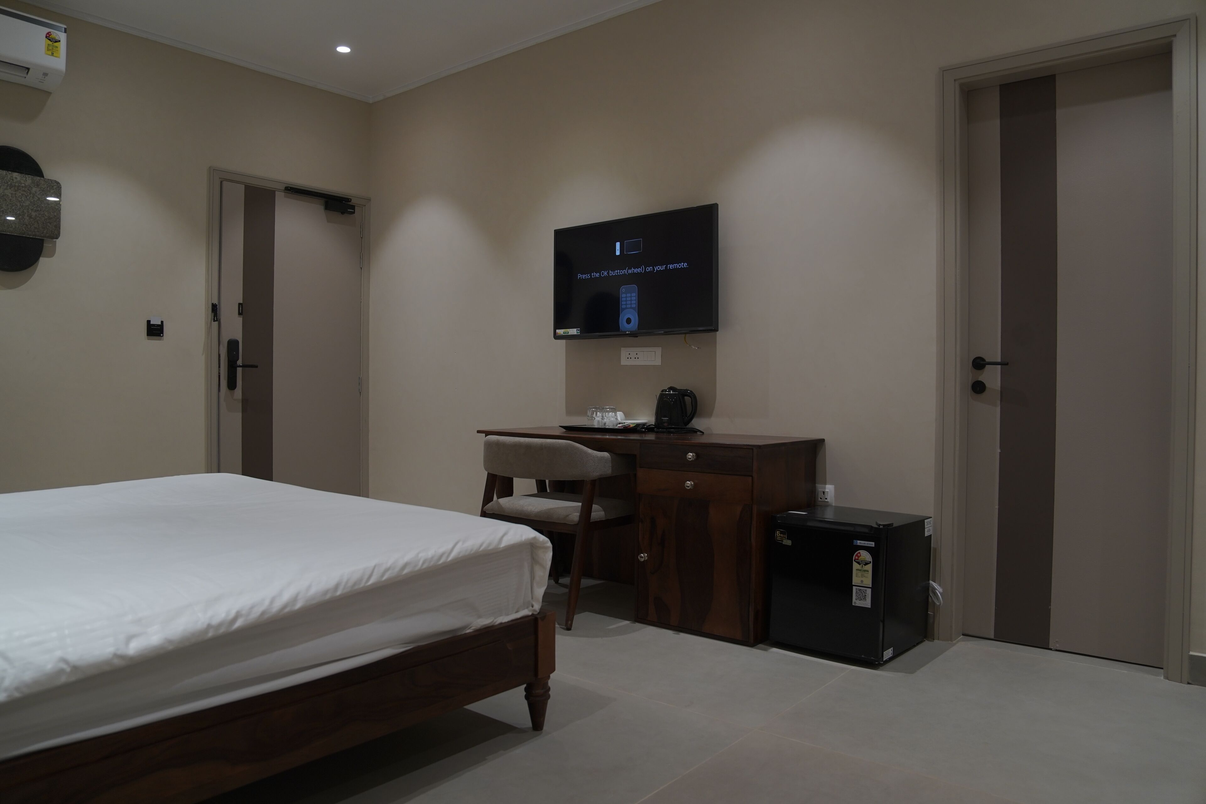 Une chambre à coucher comprenant un lit, un bureau, une chaise, un téléviseur et un petit meuble de rangement.