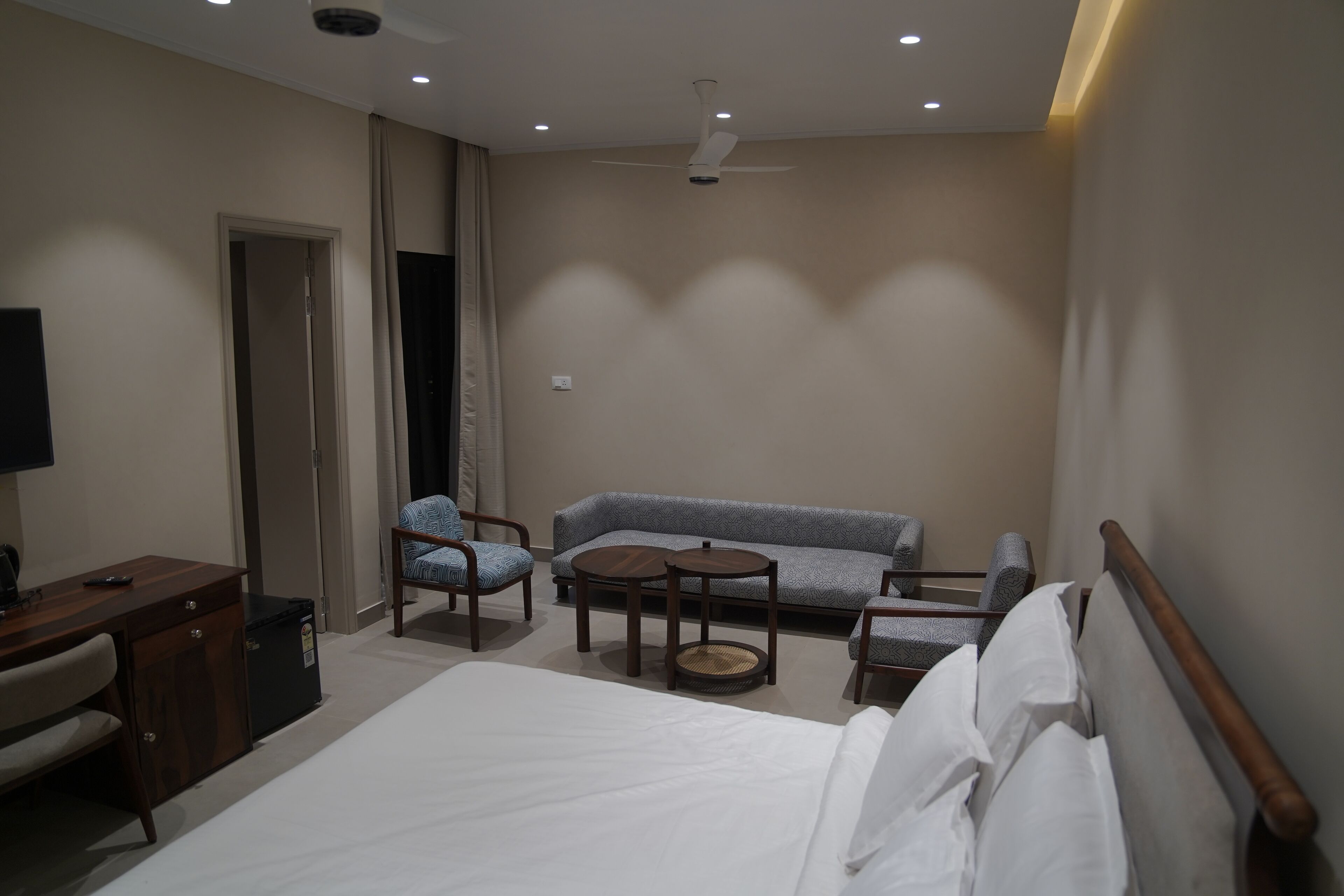 Hotellihuone, jossa on sänky, työpöytä, tuoli, sohva ja pieni pöytä.