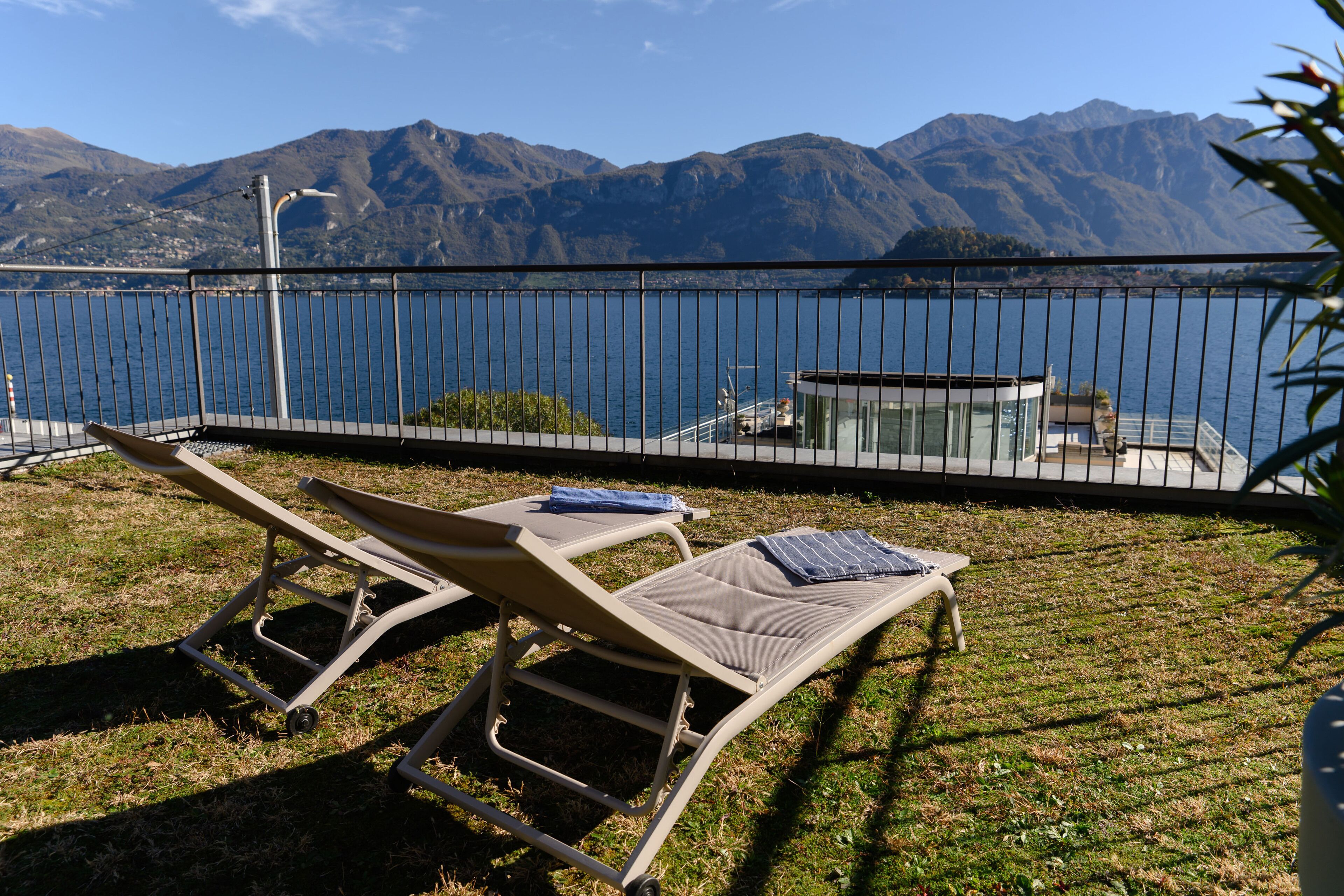 Two sun loungers with a mountain view and a body of water in the background.