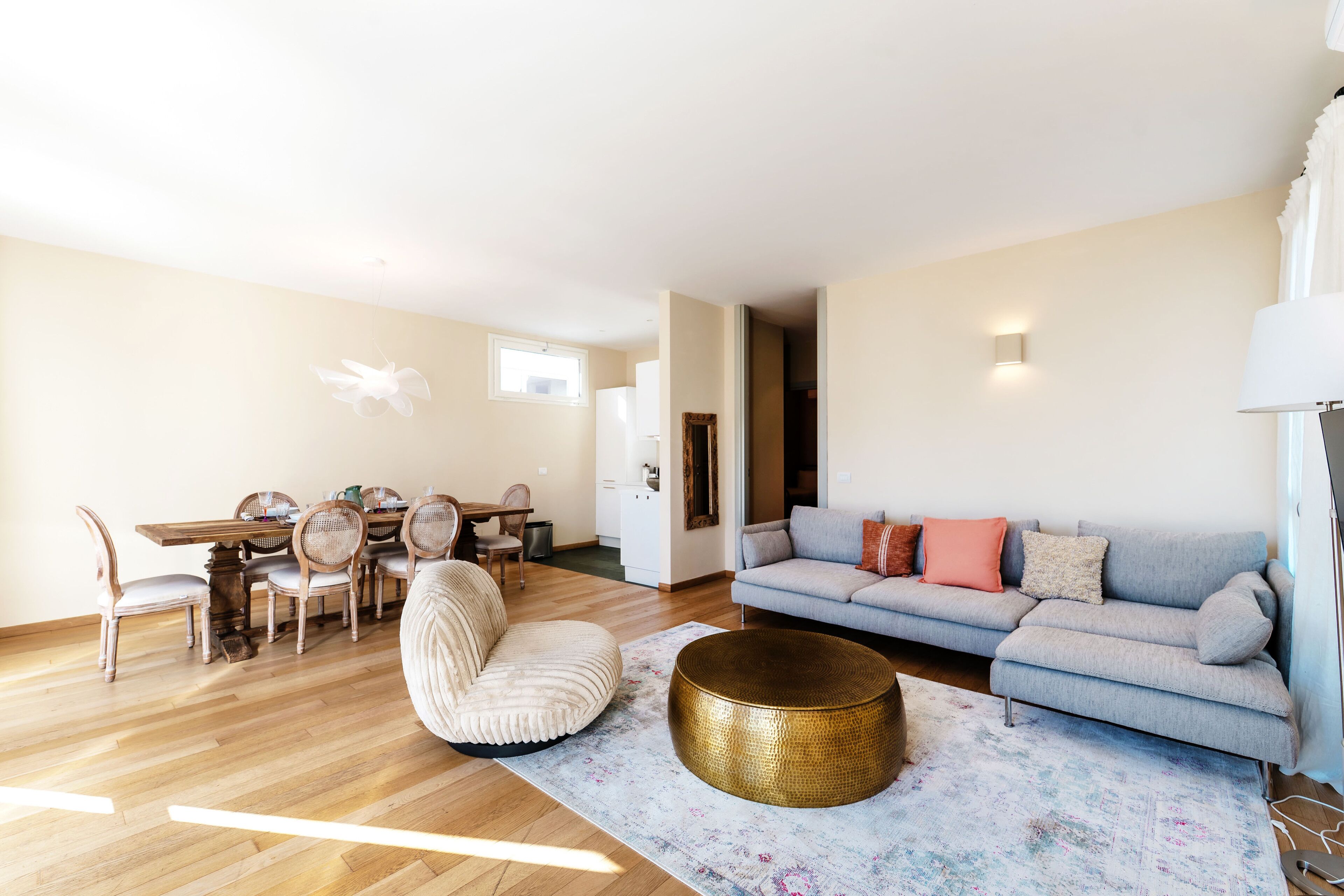 Un salon comprenant un canapé, une table basse ronde et un coin repas avec des chaises et une table.