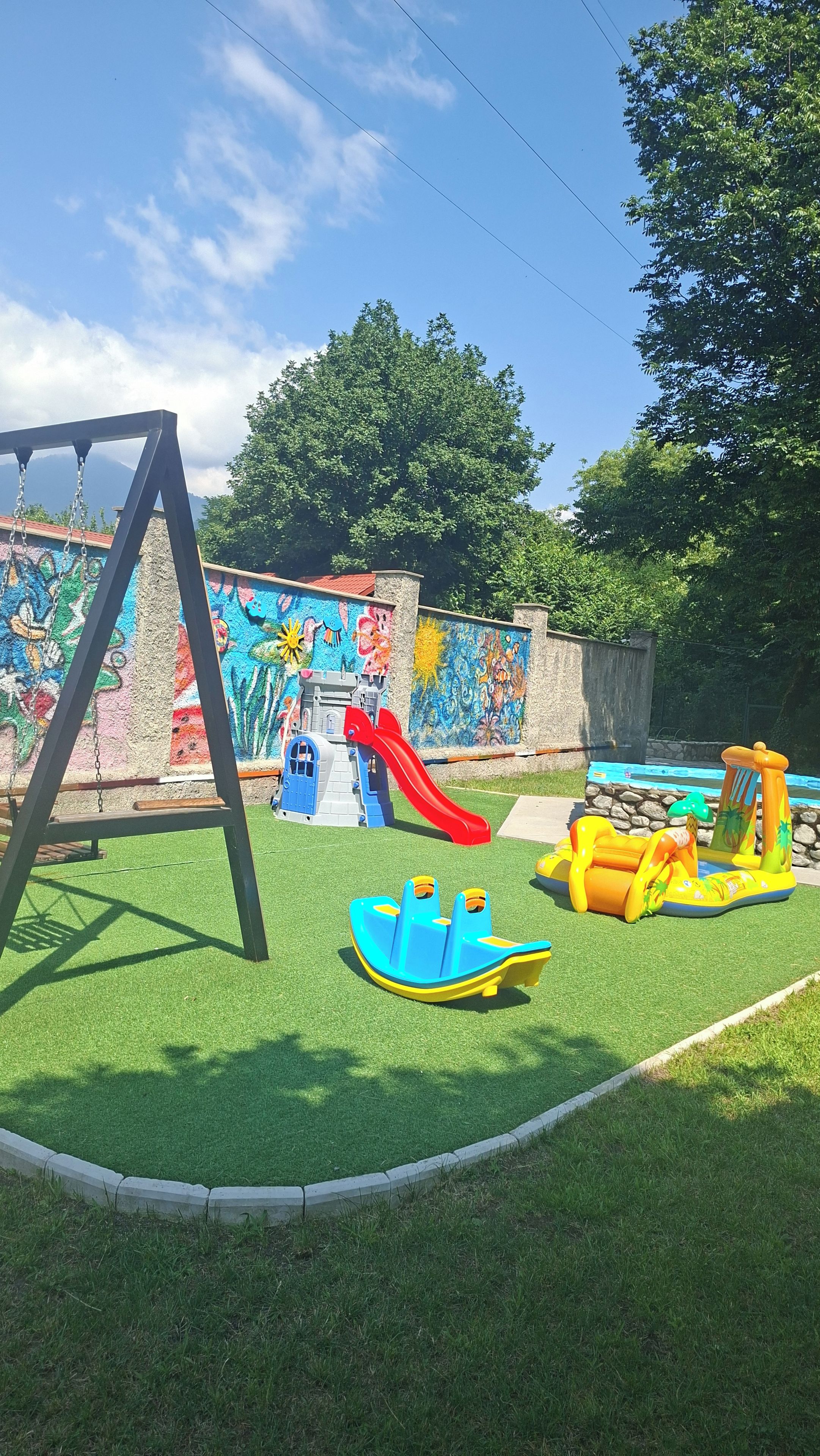 Un parque infantil con columpios, tobogán y juguetes hinchables.