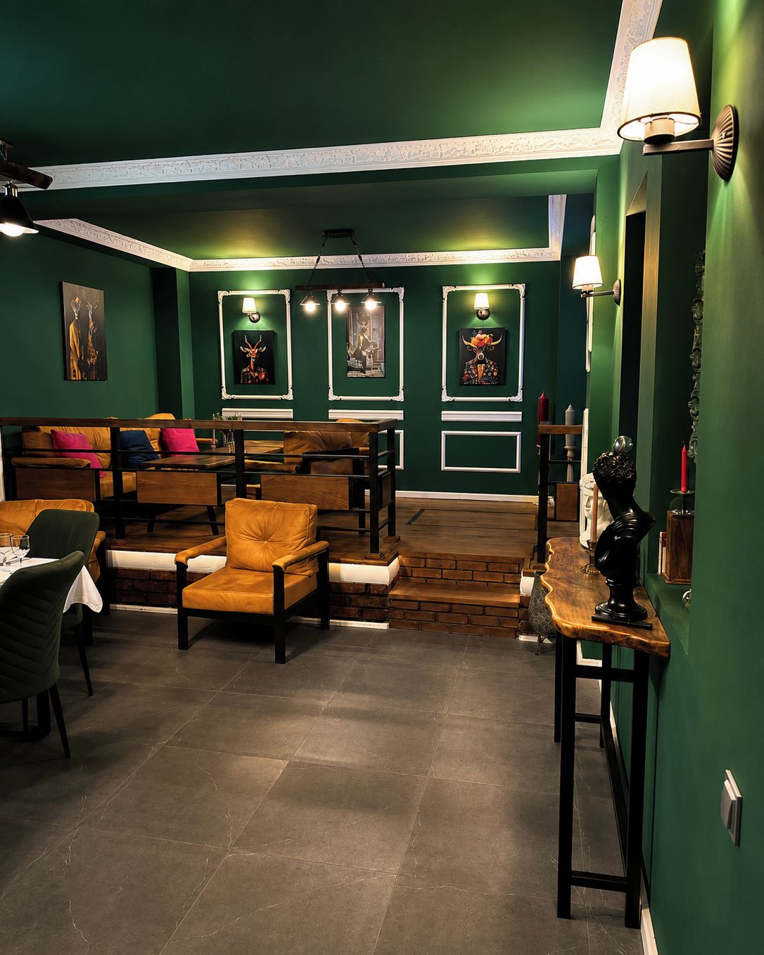 A room with green walls, a wooden bench, a table, and a lamp.