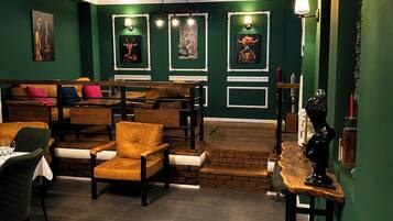 A room with green walls, a wooden bench, a table, and a lamp.