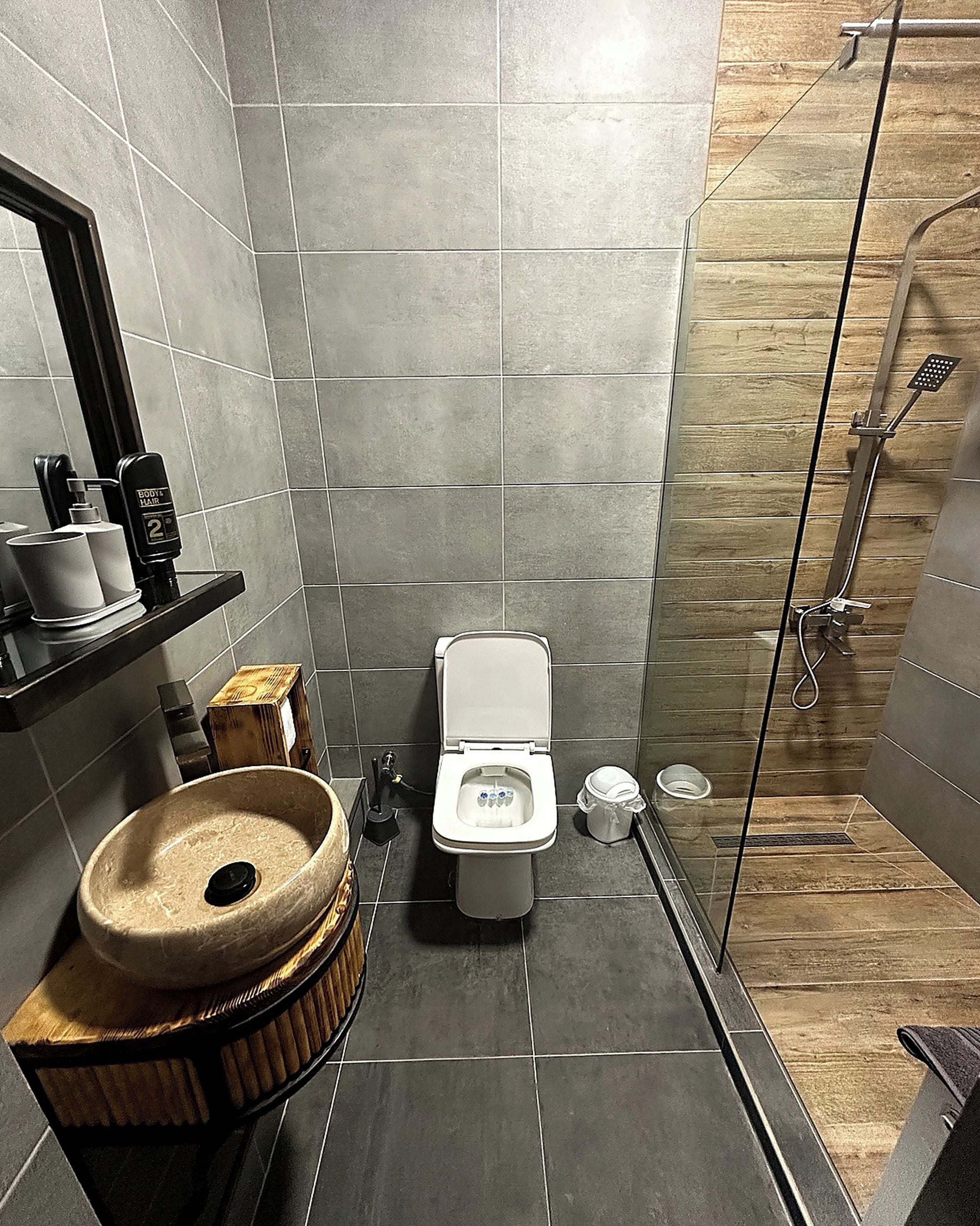 A modern bathroom with a toilet, bidet, and a wooden vanity with a sink.
