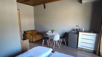 Un dormitorio con una cama grande, un escritorio pequeño, una silla, una mesa y un aparador.
