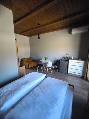 Un dormitorio con una cama grande, un escritorio pequeño, una silla, una mesa y un aparador.