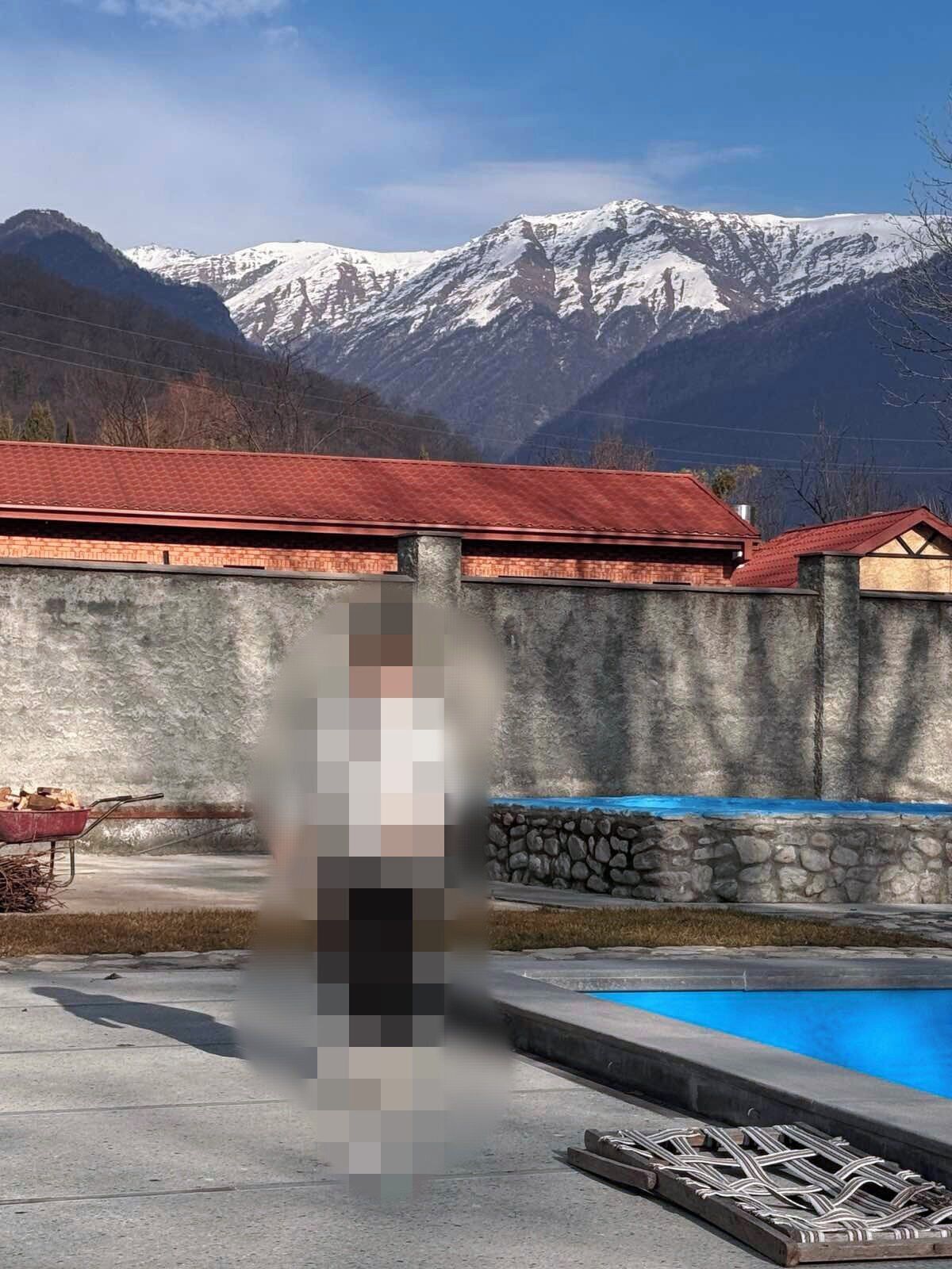 A pool area with a stone wall and a view of snow-capped mountains.