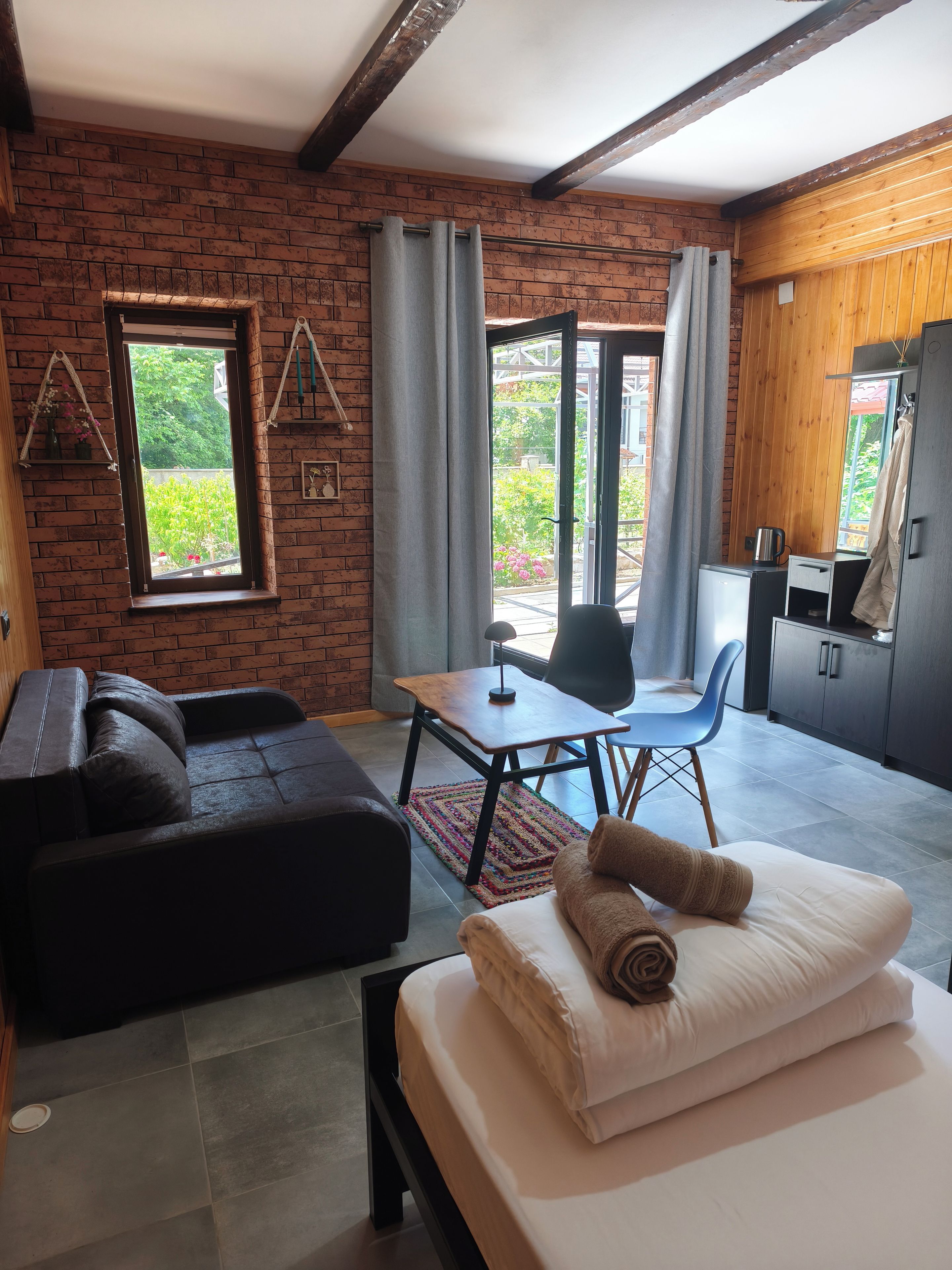 A modern room with a brick wall, a sofa, a bed, a table, and a chair.