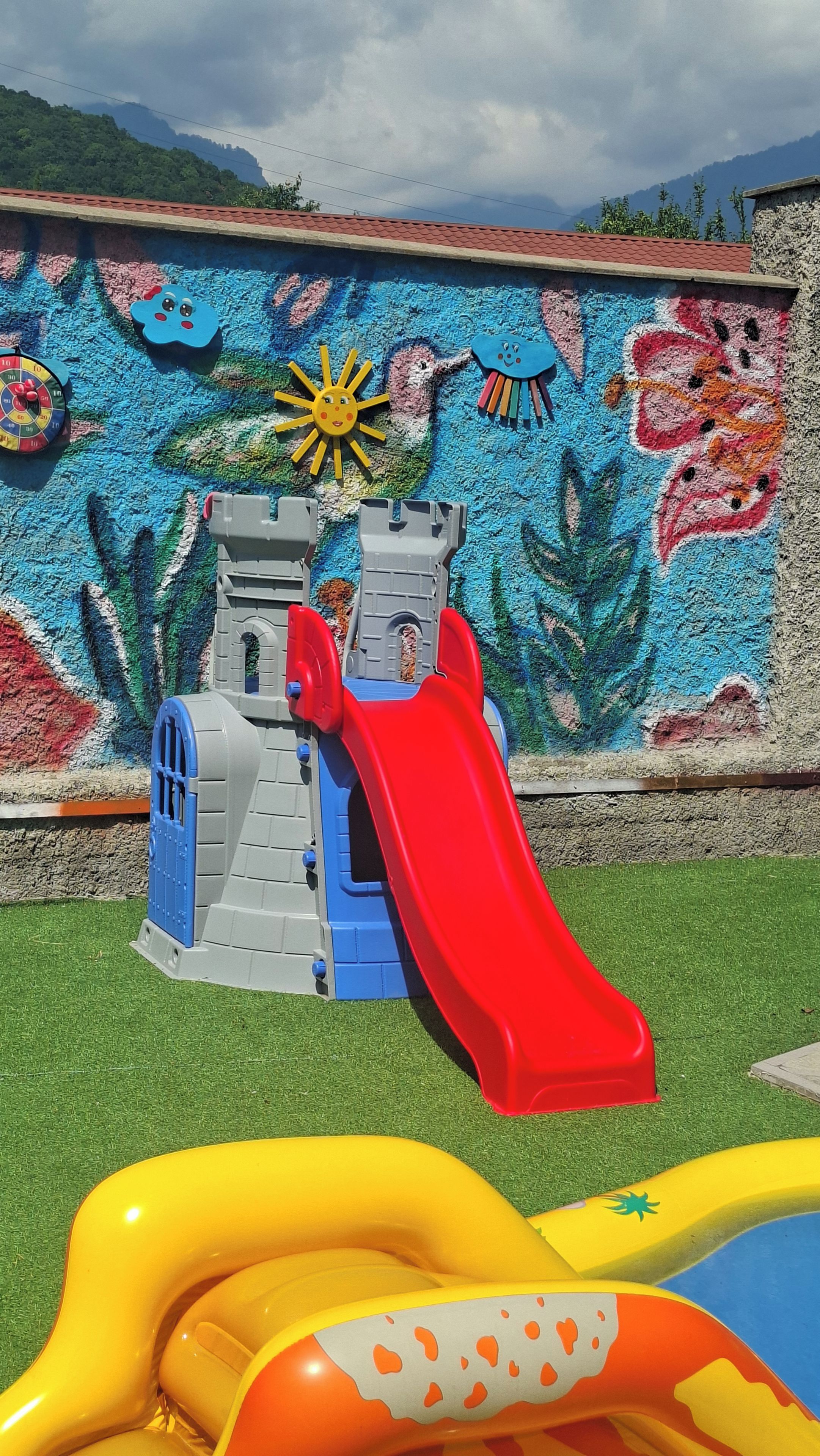 Zona de juegos infantiles con tobogán y piscina inflable.