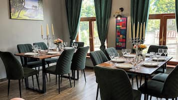 Comedor con mesa de madera dispuesta para una comida, rodeado de sillas y una araña colgante.