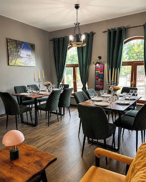 A dining area with a wooden table set for a meal, surrounded by chairs, and a chandelier above. - Arazani (Lagodekhi)