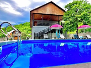 A modern building with a pool, lounge chairs, and umbrellas. - Arazani (Lagodekhi)