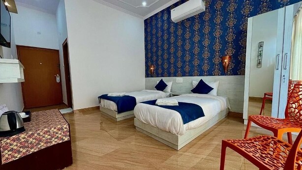 Een hotelkamer met twee bedden, een houten vloer, een blauwe behang muur en een rode stoel.