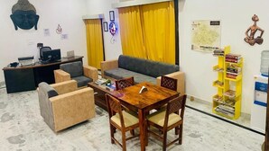 Een moderne woonkamer met een bank, fauteuils, een houten eettafel en een klein bureau met een computer.