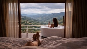 A bedroom with a large bed, a bathtub, and a balcony with a view of mountains. - Cozy Homey Doichang (Mae Suai)