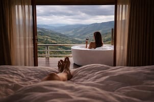 Un dormitorio con una cama grande, una bañera y un balcón con vistas a las montañas.