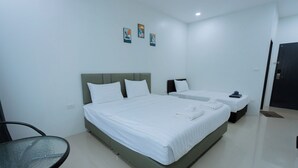 A modern hotel room with a large bed, a smaller bed, a glass table, and a chair. - The Rich Hotel (Surin)