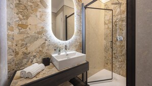 A modern bathroom with a marble sink, a large mirror, and a glass-enclosed shower. - Relais Pinciana (Rome)