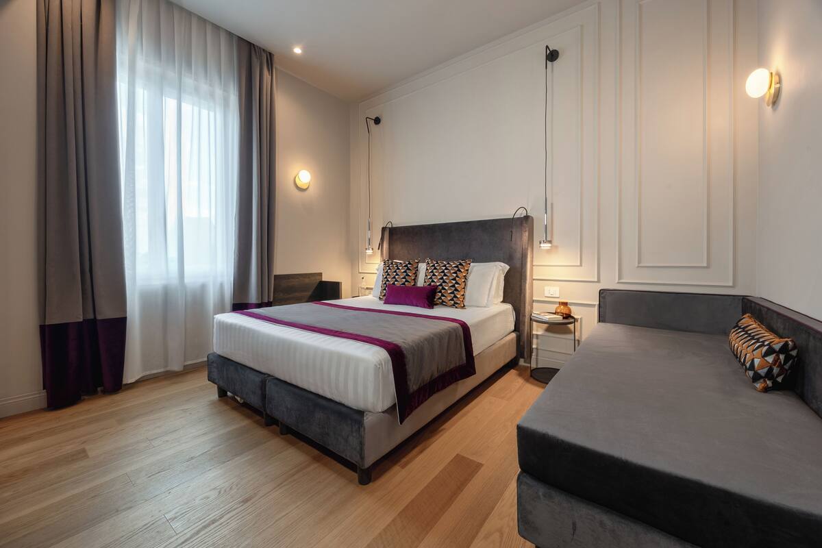 A modern bedroom with a large bed, bedside tables, and a sofa.