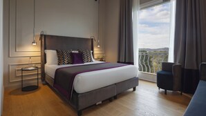 A modern hotel room with a large bed, a side table, a chair, and a balcony with a view. - Relais Pinciana (Rome)