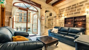 Un salon chaleureux avec un mur en pierre, un canapé en cuir, une table basse en bois et une cheminée.